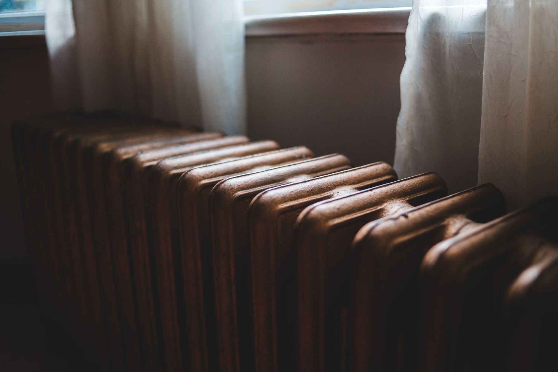Locataire emmitouflé dans un pull à côté d'un radiateur froid dans son appartement