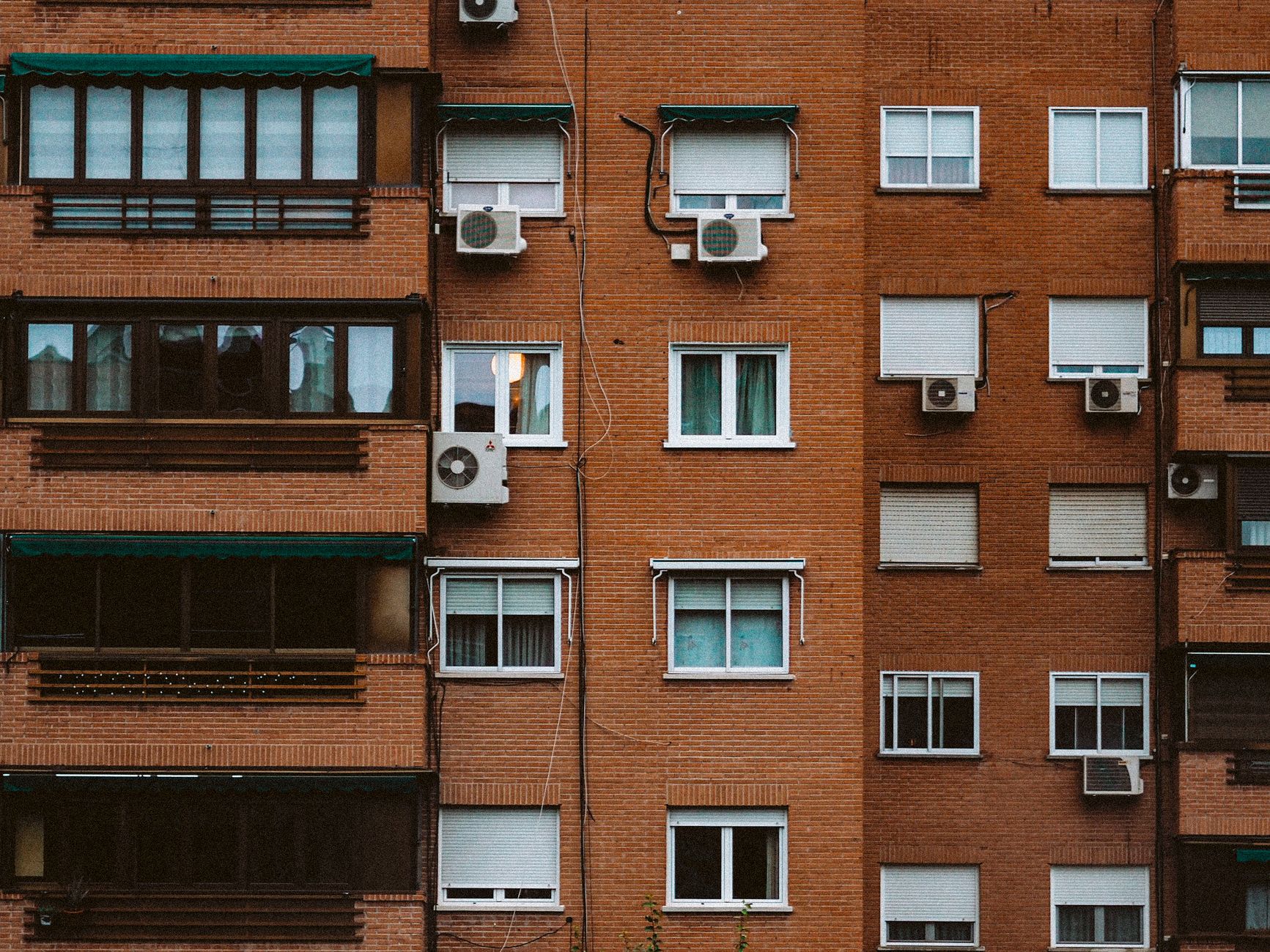 Un climatiseur mobile posé près d'une fenêtre dans un appartement en brique typique du Nord