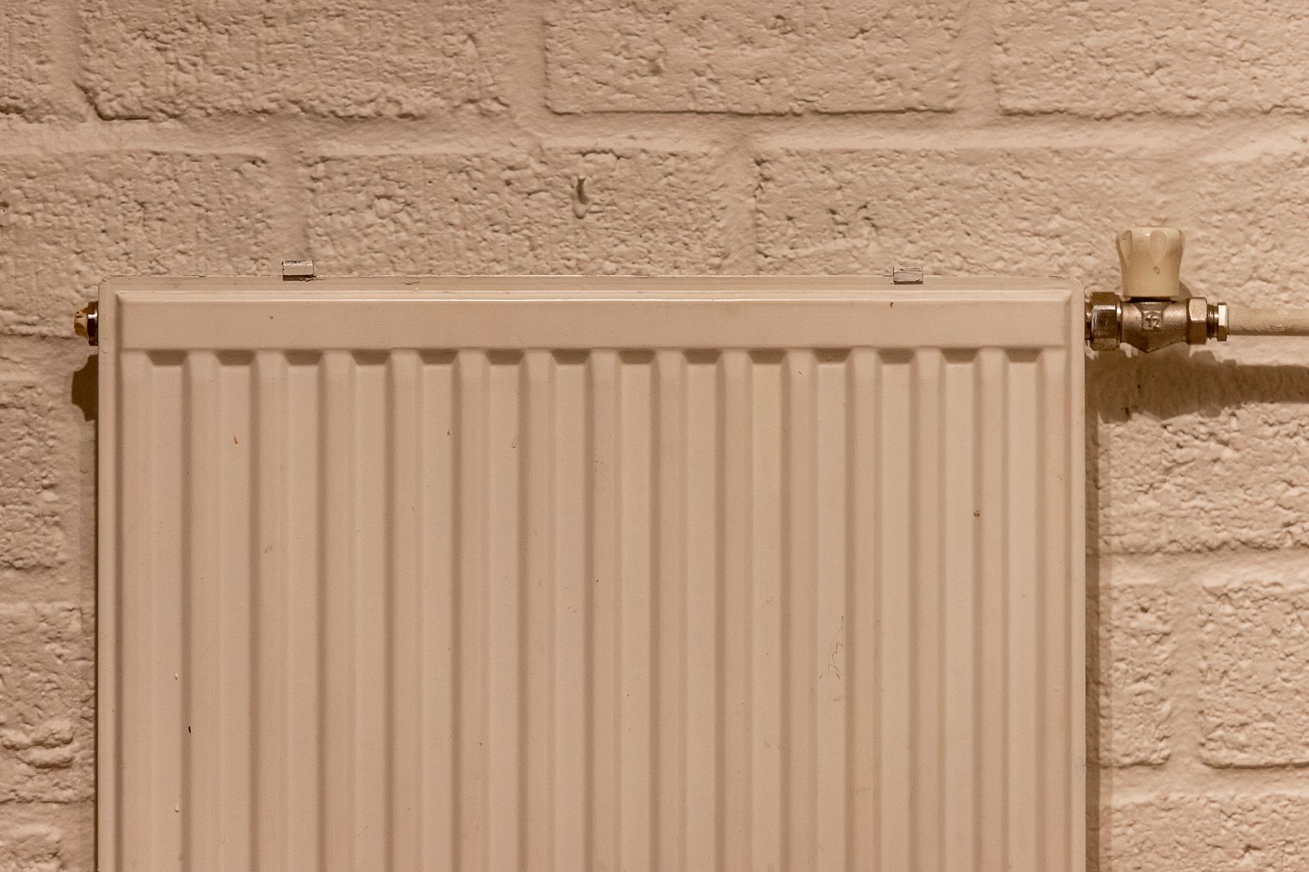 Gros plan sur un radiateur de chauffage central et sa robinetterie, illustrant l'entretien du circuit d'eau