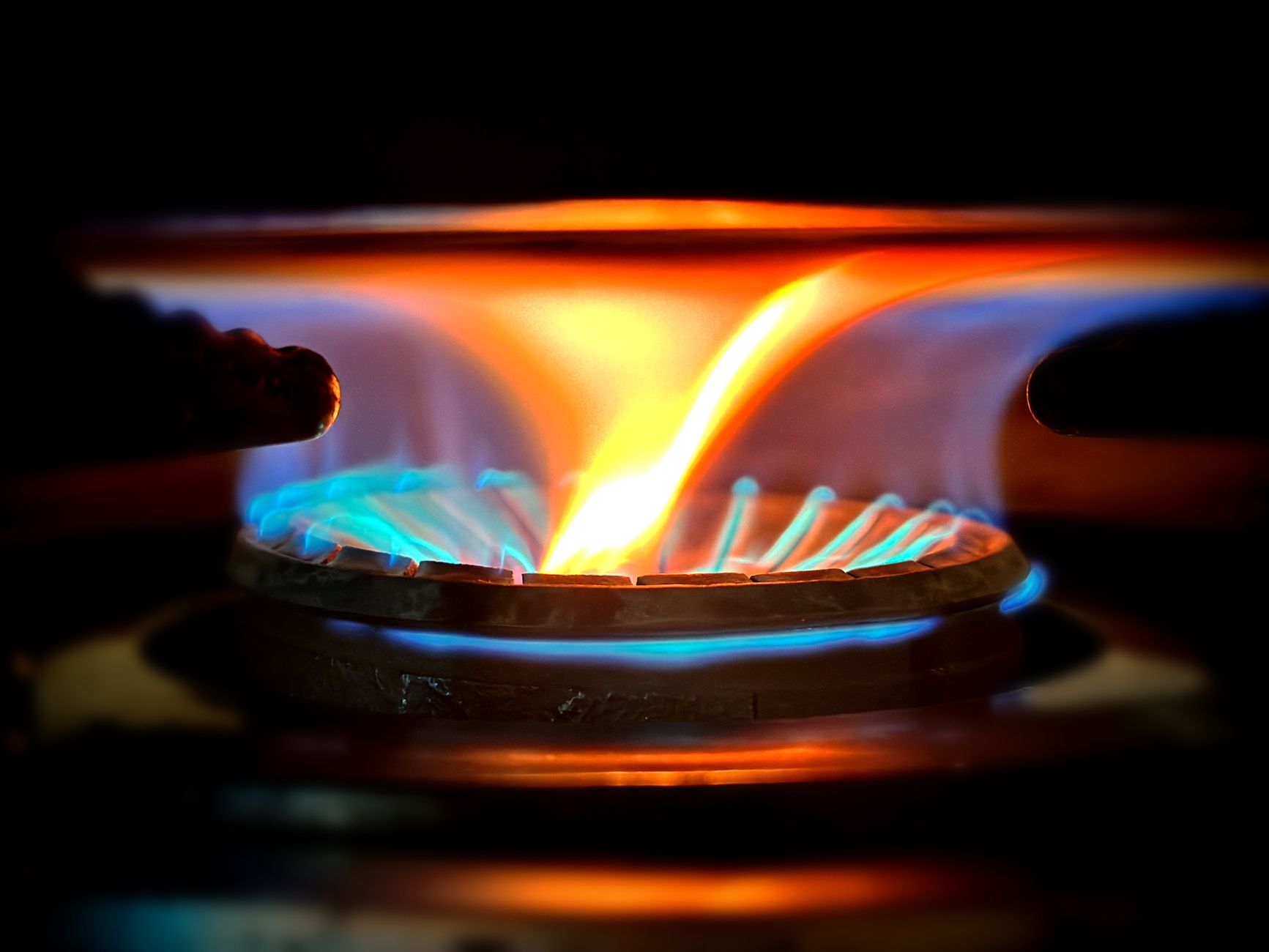 Gros plan sur les flammes bleues et orangées d'un brûleur de cuisinière à gaz allumé dans un logement